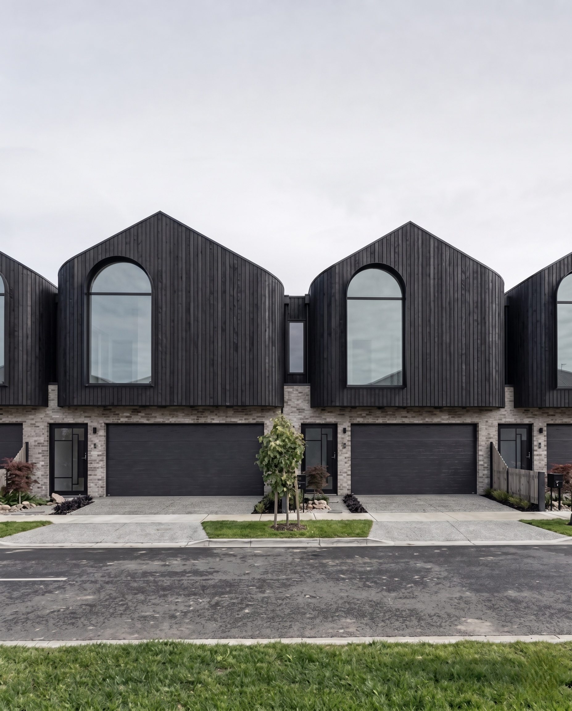 Multi-unit townhouses with charred timber gables and arched windows